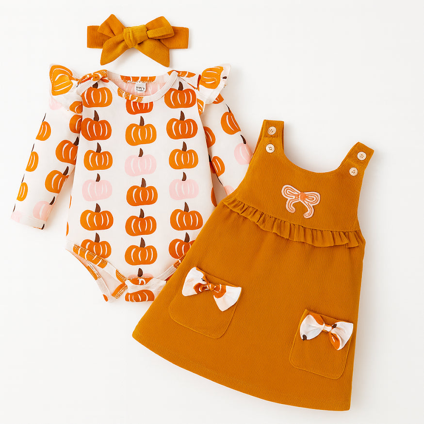 Pumpkin Harvest 3-Piece Baby Dress Outfit includes an orange bow headband, long-sleeve bodysuit with orange and pink pumpkin prints, and orange pinafore dress with bows and chest ruffle. Made of soft, breathable cotton. Available in size 9-12M.
