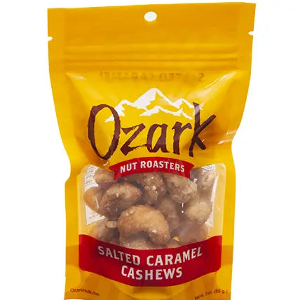 Yellow 3oz resealable Ozark Salted Caramel Cashews bag with clear window; Ozark logo and product name in bold.
