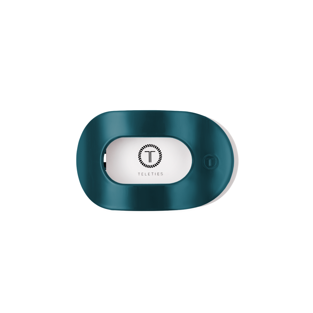 Teal With It Small Flat Round Hair Clip holder with a teal oval design, transparent window showing the white Teleties logo, and a small button on the right side. Available in small size.