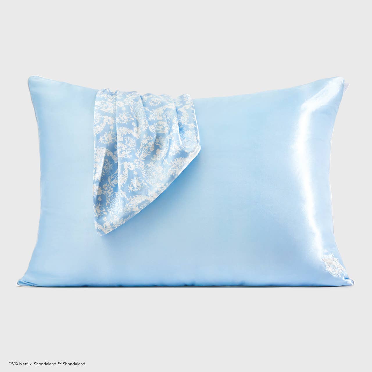 Light blue satin pillowcase with one corner in shiny, patterned blue and white. Available sizes: standard, king.