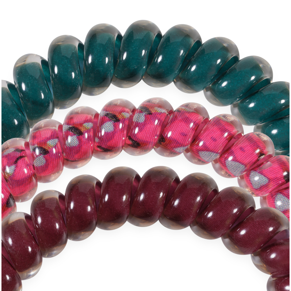 The Harvest Hues Small Hair Ties set includes three small spiral coil hair ties in green, pink with a floral print, and maroon. Available in small size.