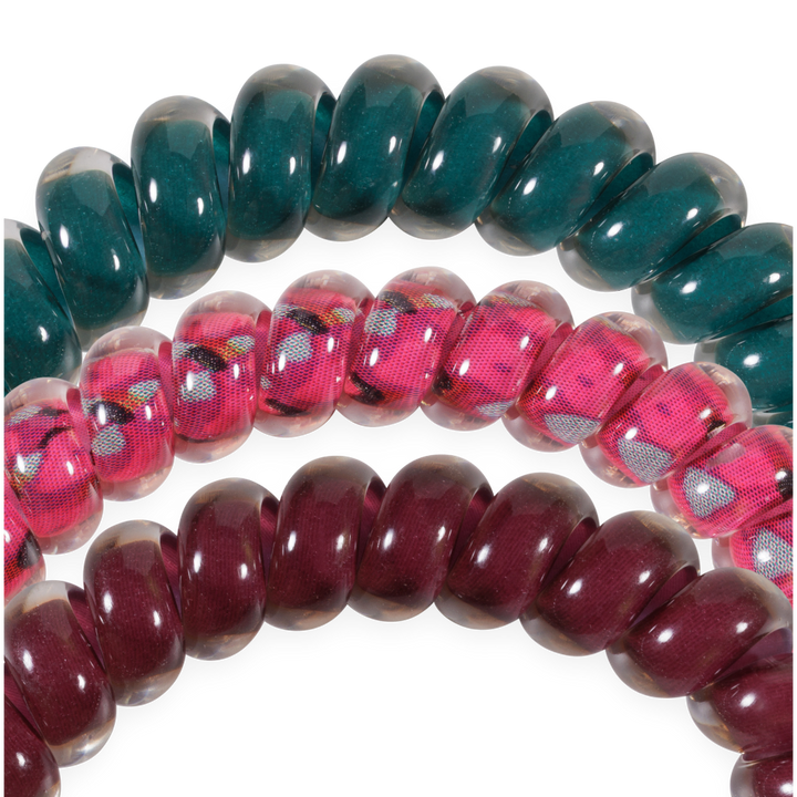 The Harvest Hues Small Hair Ties set includes three small spiral coil hair ties in green, pink with a floral print, and maroon. Available in small size.