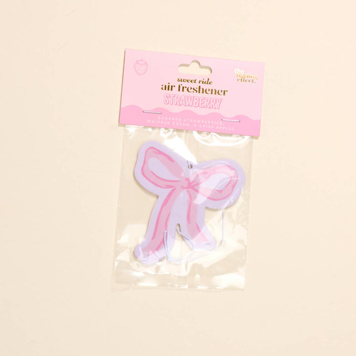Sweet Ride Car Air Freshener–Bow Pink: pink bow shape, clear packaging, pink "STRAWBERRY" label. Size options available.