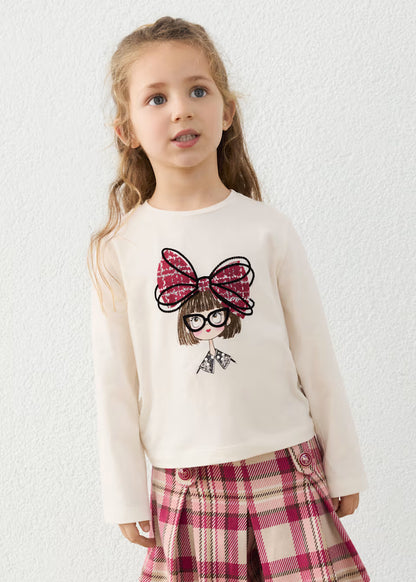 Little Girl Doll Long Sleeve T-Shirt with Bow in cream, features cartoon doll print and red plaid bow. Available in sizes 2T–6T.