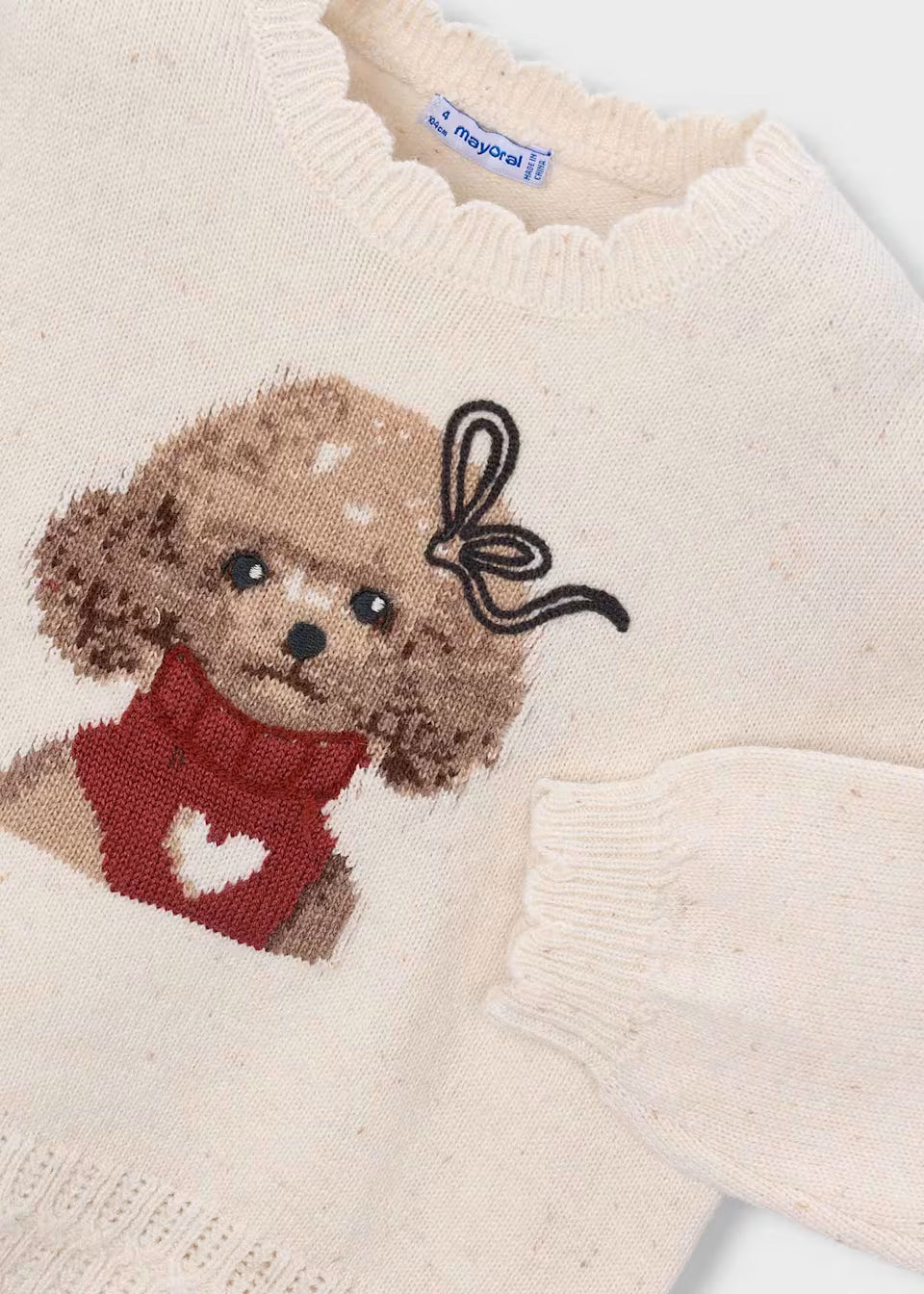 Cream-colored intarsia knit sweater with a brown dog in a red heart sweater on the front, black bow detail, ribbed cuffs, and scalloped neckline. Available in sizes 2T–6.