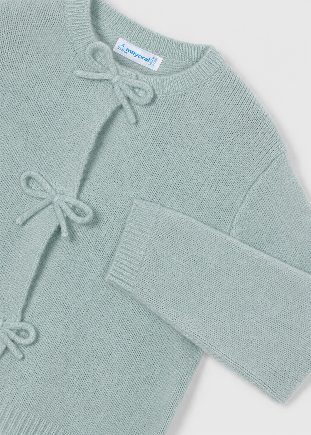 Dusty teal knit baby cardigan with three bow ties on the front and a “mayoral” tag at the neckline. Available in sizes 0-24 months.