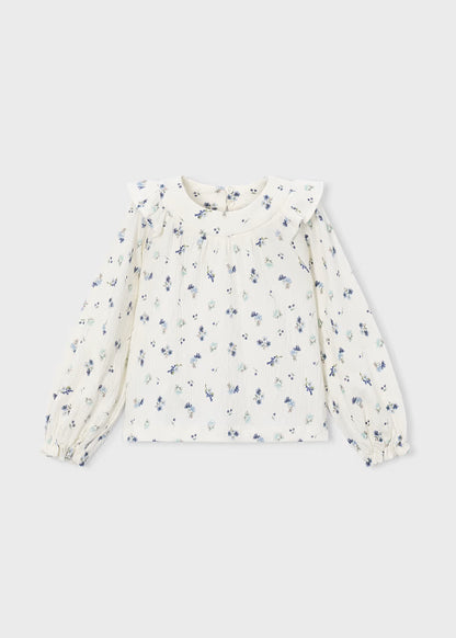 White crinkle cotton blouse with long sleeves, ruffled collar, small blue floral print, front pleats, ruffle accents, and elastic cuffs. Available in sizes 2T-6X.