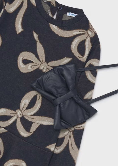 Dark sweater-style dress with beige bow print, includes matching black faux leather bow bag. Available in sizes 2T–6T.
