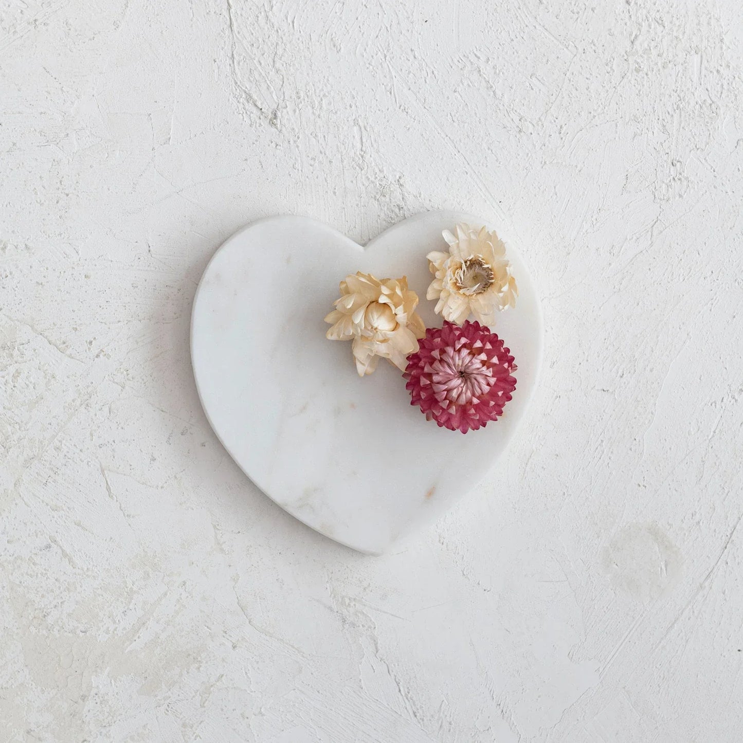 Marble heart-shaped dish with textured white surface, two cream and one pink dried flower. Available in small and large sizes.