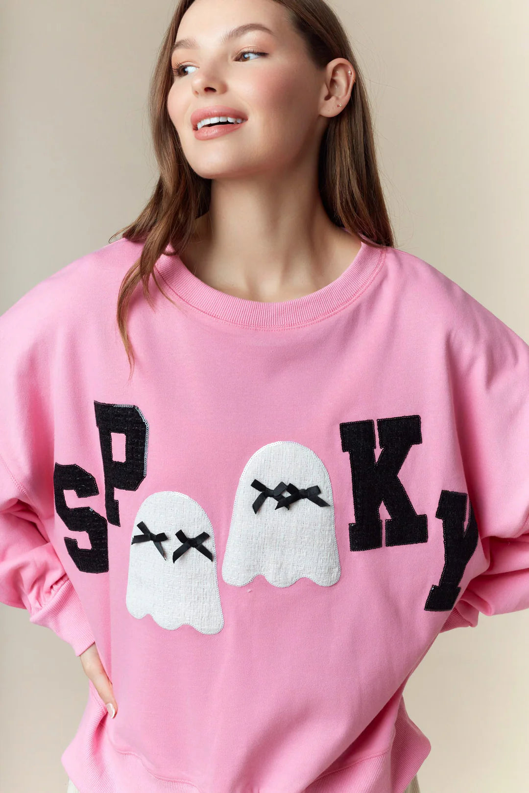 Spooky Boo Pink Patch Sweatshirt—oversized pink Halloween pullover with bold black “SPOOKY” text and two white ghost illustrations with closed eyes and lace patches at the center. Available in sizes S-XXL.