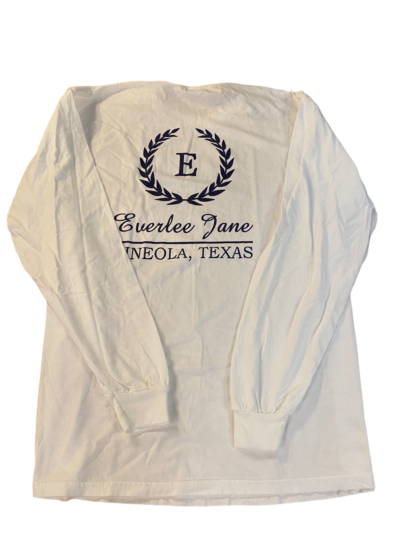 Unisex fit white long-sleeve Everlee Jane T-Shirt LS with a monogram "e" inside a laurel wreath and text "everlee jane, enola, texas" printed in dark ink on.