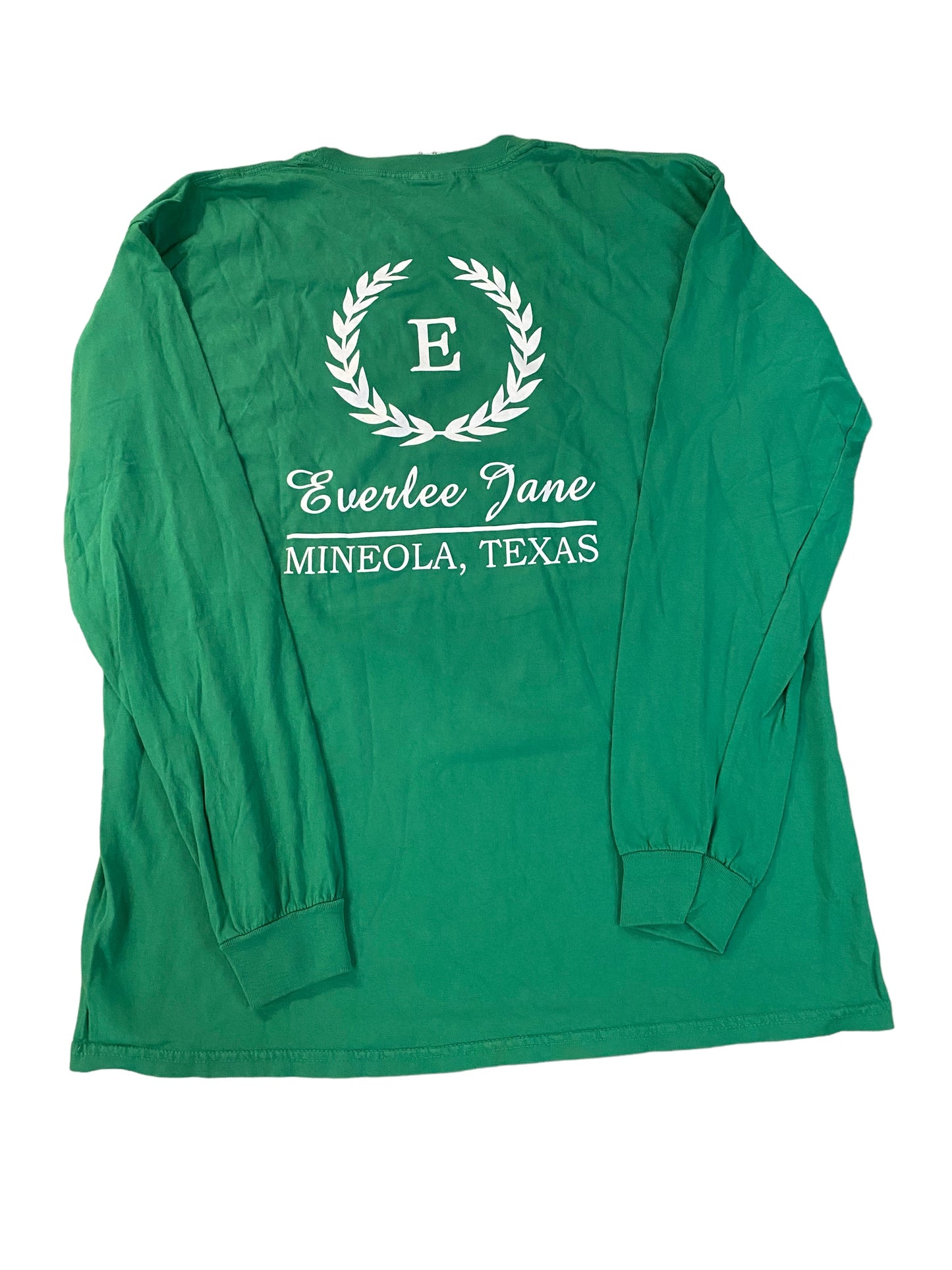 Unisex fit green long-sleeve Everlee Jane T-Shirt LS with a white printed logo featuring a wreath and the text "e everlee jane mineola, texas" within the wreath on the