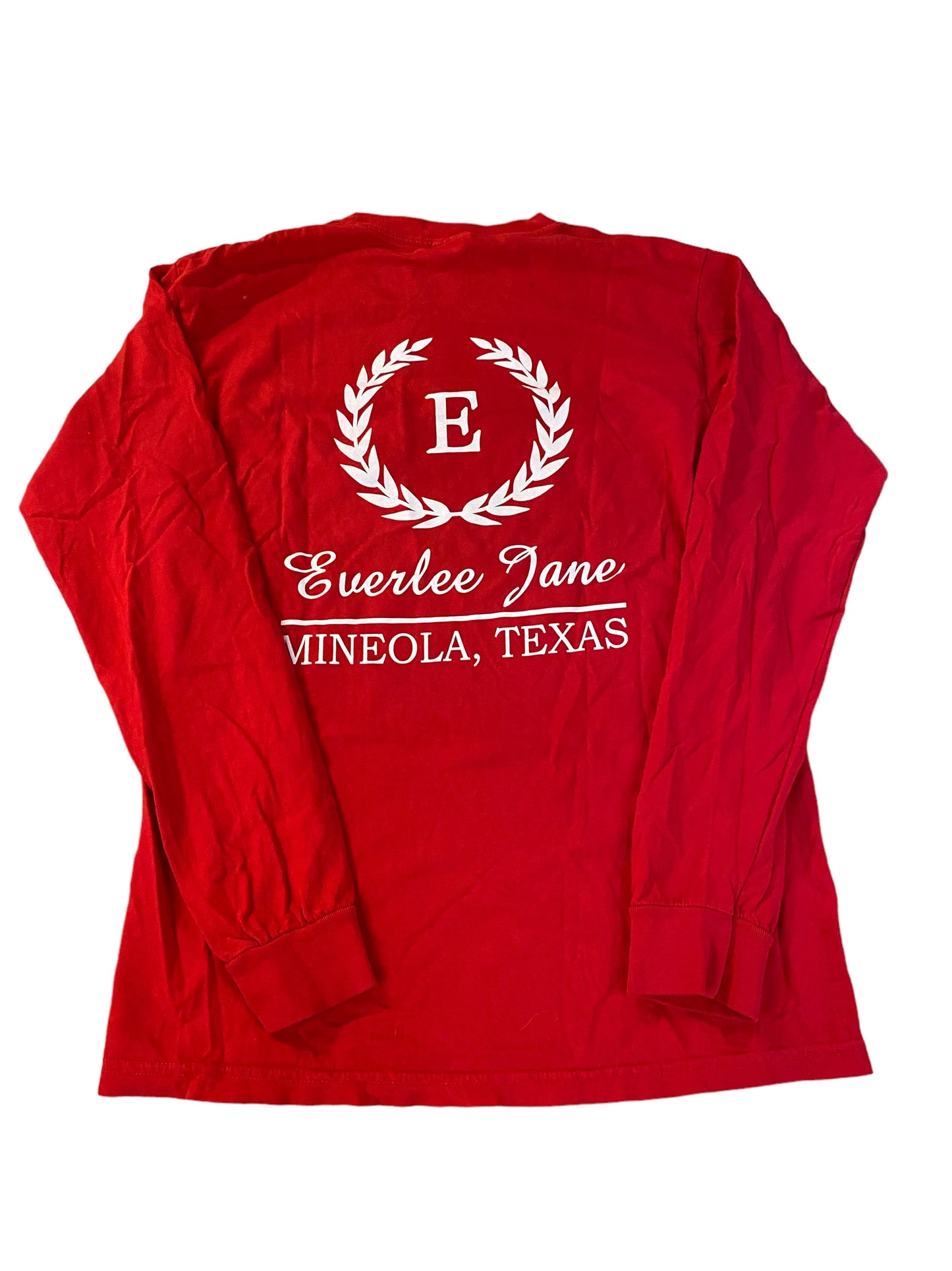 A red long-sleeve Everlee Jane T-Shirt LS with the text "everlee jane mineola, texas" encircled by a laurel wreath graphic, displayed on a white background.