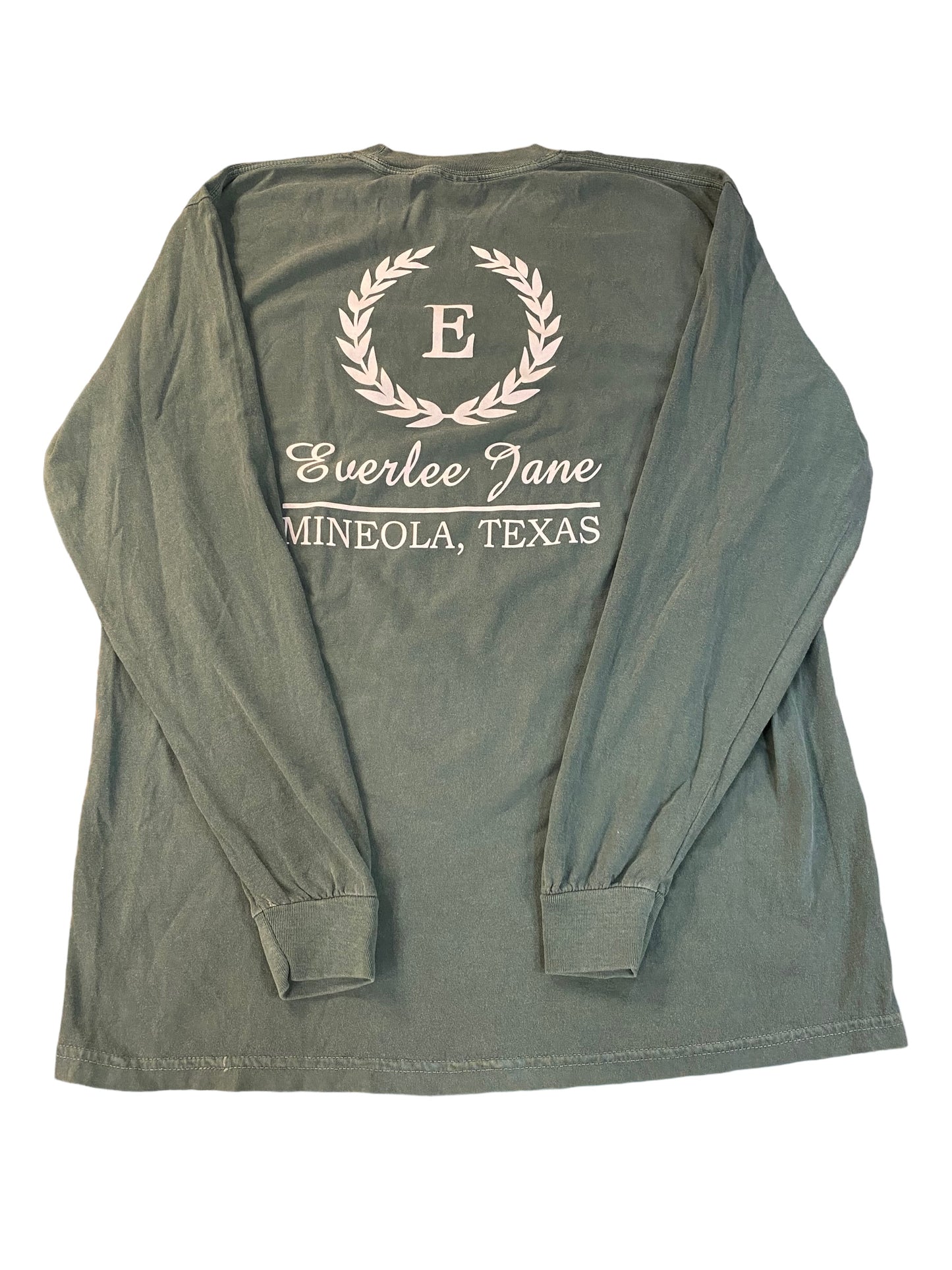 A green long-sleeved Everlee Jane T-Shirt LS displayed flat, featuring a white printed design with the text "everlee jane" encircled by a laurel wreath and "mineola.