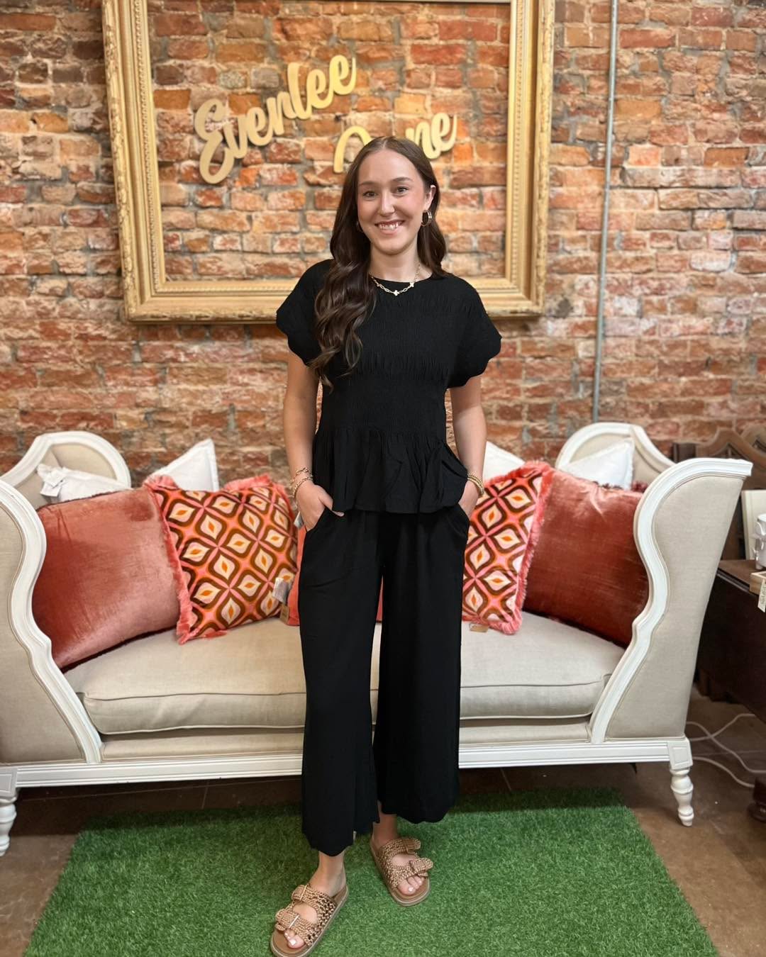 The Amelia Smocked Peplum Top features smocked detailing and a peplum silhouette. Available in sizes XS–XL.