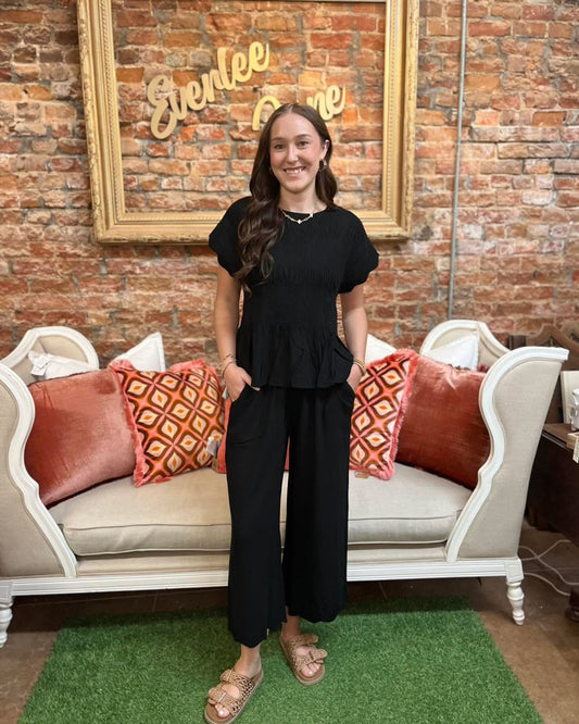 The Amelia Smocked Peplum Top features smocked detailing and a peplum silhouette. Available in sizes XS–XL.