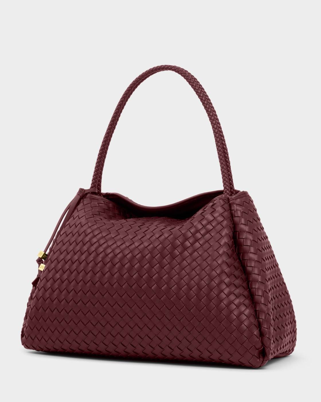 The Nova Hand Woven Large Shoulder Bag in cherry features a curved silhouette, woven vegan leather, braided handle, and subtle gold zipper accent. Available in large size.