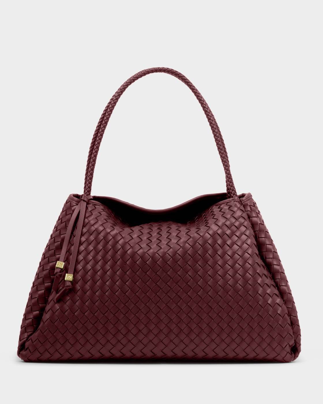 The Nova Hand Woven Large Shoulder Bag in Cherry features intricately woven vegan leather, a braided handle, and two leather tassels. Available in large size.