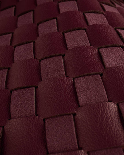Close-up of interwoven cherry vegan leather strips in a basket weave pattern on the Nova Hand Woven Top Handle Bag | Cherry. Available in small and medium sizes.