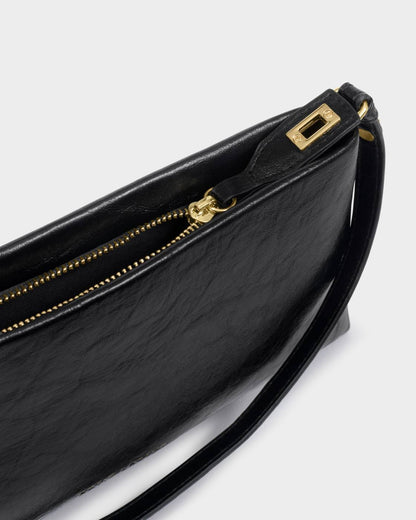 Orin Twist Lock Small Shoulder Bag in black vegan leather with gold zipper and detailing, slim design, wrist strap, versatile as clutch or shoulder bag. Available in small size.