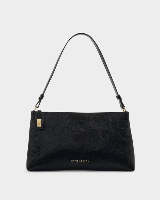 The Orin Twist Lock Small Shoulder Bag is a black vegan leather shoulder bag with a short strap, gold twist lock hardware, a small side tag, and “KATIE LOXTON” stamped in gold at the bottom center. Available in small size.