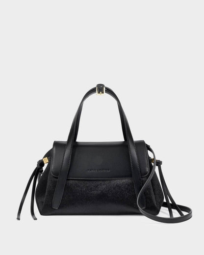 Alyssa Faux Pony Top Handle Bag in black faux pony hair and leather with gold hardware, top handle, detachable crossbody strap, flap closure, and side tassel details. Sizes available: [insert sizes].