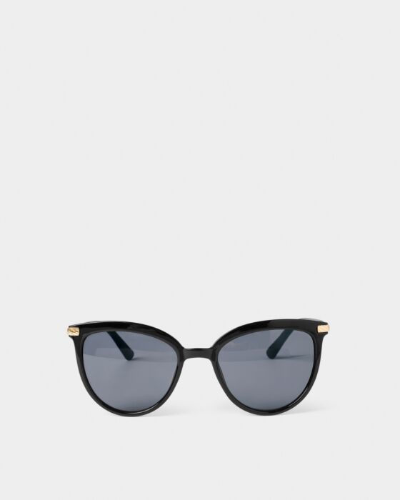 Ravello Sunglasses: black cat-eye, dark round lenses, gold temple accents, recycled materials. Sizes: S/M, M/L. 2 colors.