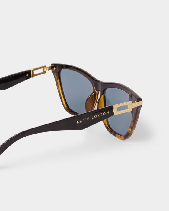 Marbella Sunglasses: tortoiseshell frame, blue UV400 lenses, gold accents, "Katie Loxton" on arm. Recycled materials. Sizes: S/M/L.