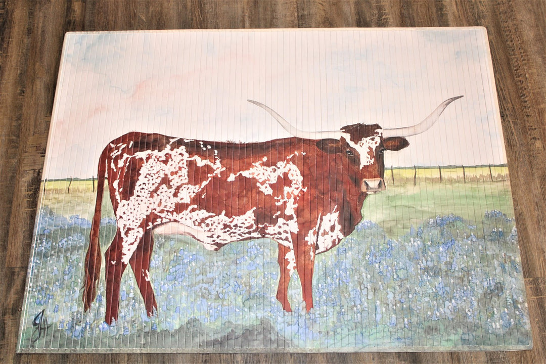 Queen in Bluebonnets Bamboo Mat" features a brown and white longhorn cow amid blue flowers on a green background with a light blue sky. Available sizes: 24"x36", 36"x60".