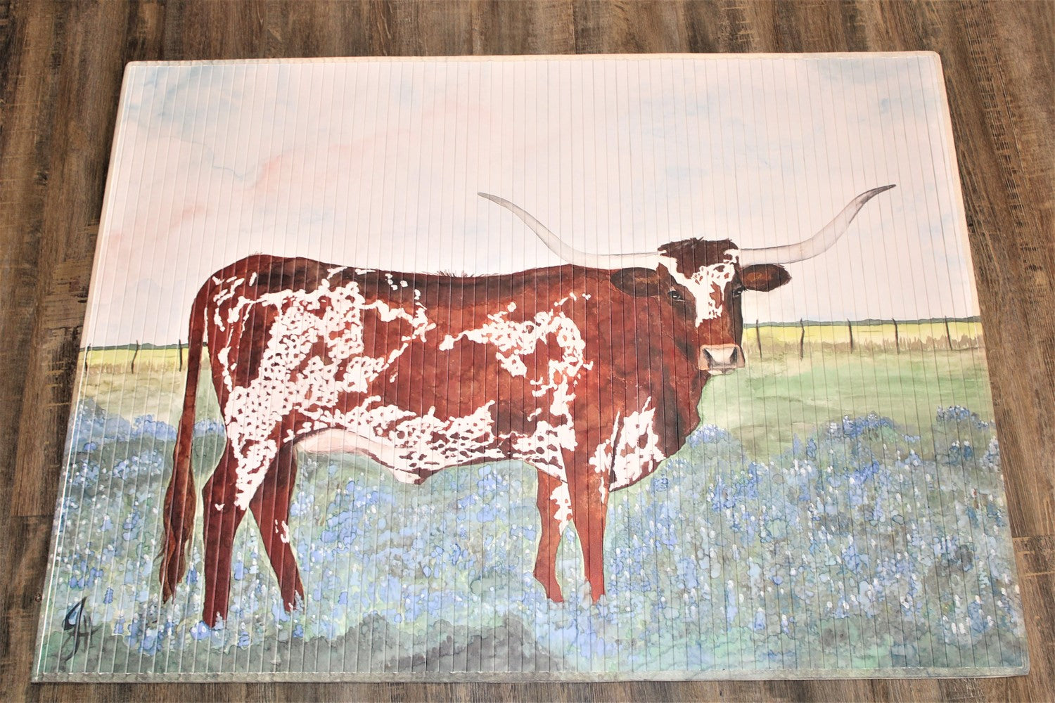 Queen in Bluebonnets Bamboo Mat" features a brown and white longhorn cow amid blue flowers on a green background with a light blue sky. Available sizes: 24"x36", 36"x60".