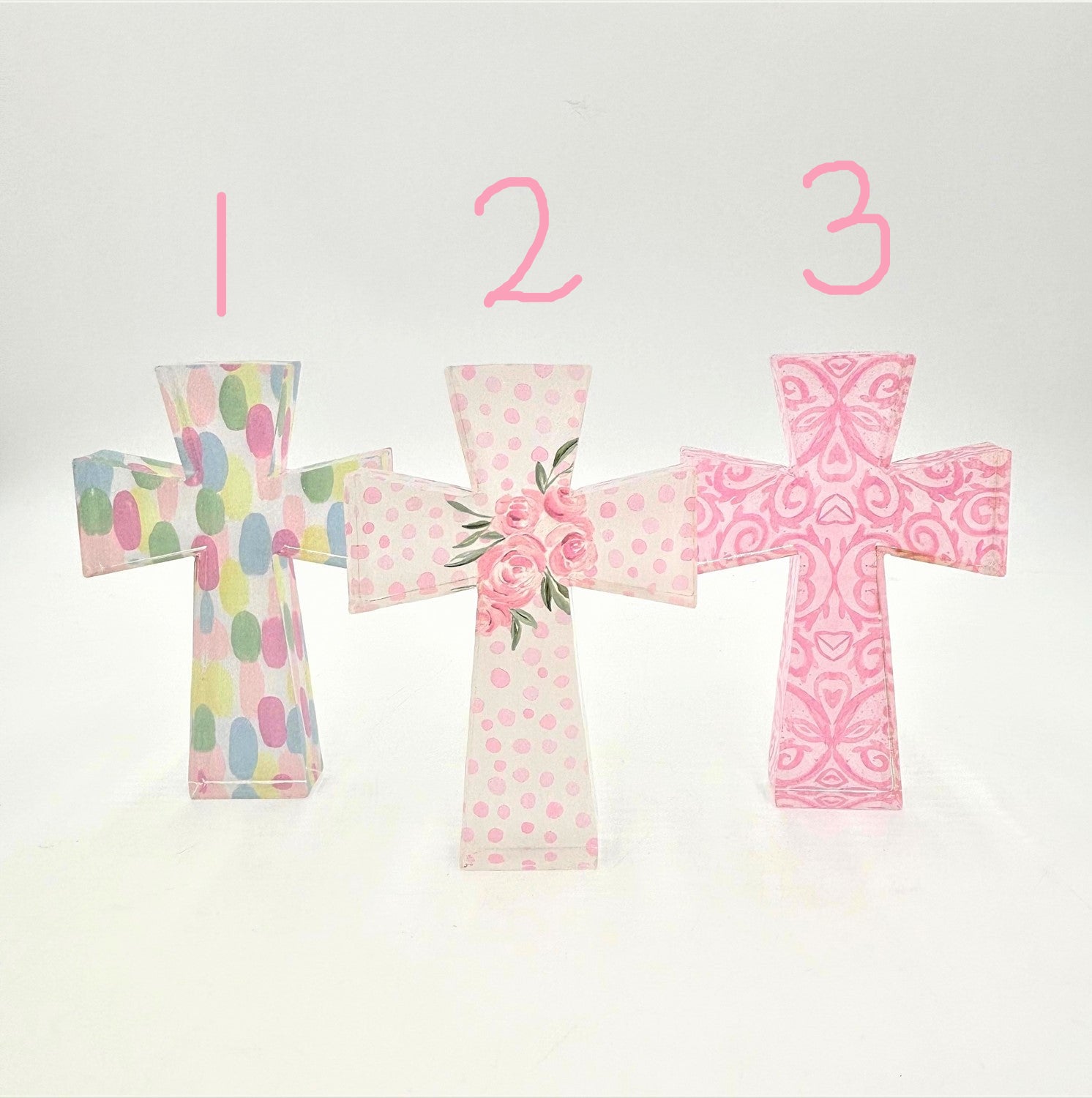 The Pastel Cutout Acrylic Crosses feature three designs: Cross 1 with pastel polka dots, Cross 2 with pink roses on a pink polka dot background, and Cross 3 with a vibrant pink paisley design on white. Sizes available: Small, Medium, Large.