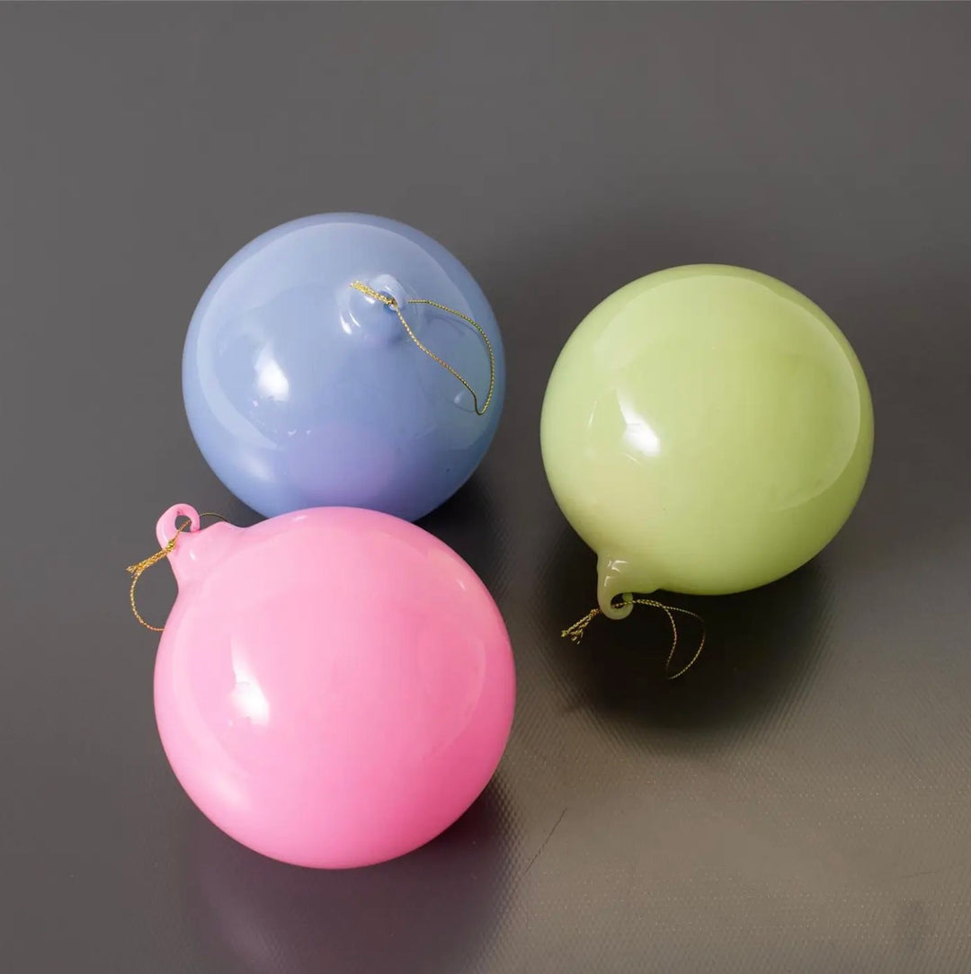 Pastel pink, light blue, and lime green hand-blown glass ornaments with gold hanging strings.
