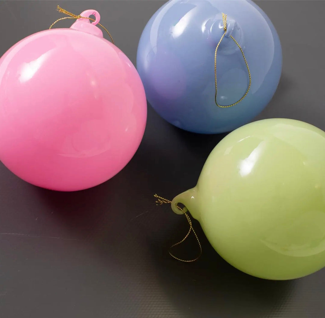 Three Hand Blown Glass Ornaments in pink, blue, and light green with gold hanging strings.