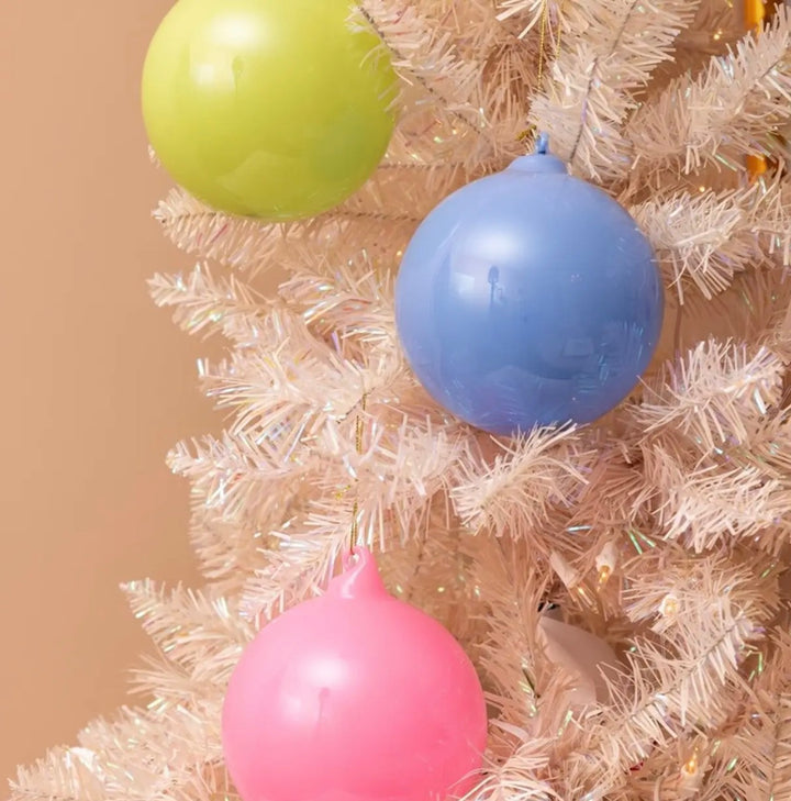 Hand blown glass ornaments in lime green, light blue, and pink, spherical.