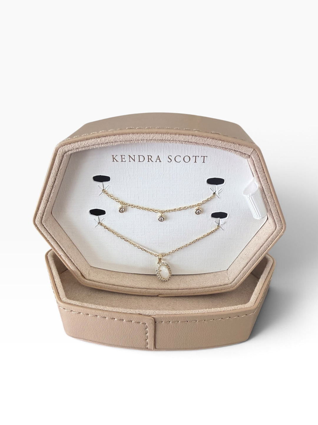 Two delicate gold necklaces, one with three small crystals and one with a stone pendant, in a Kendra Scott Daphne Amelia Jewelry Box Set.