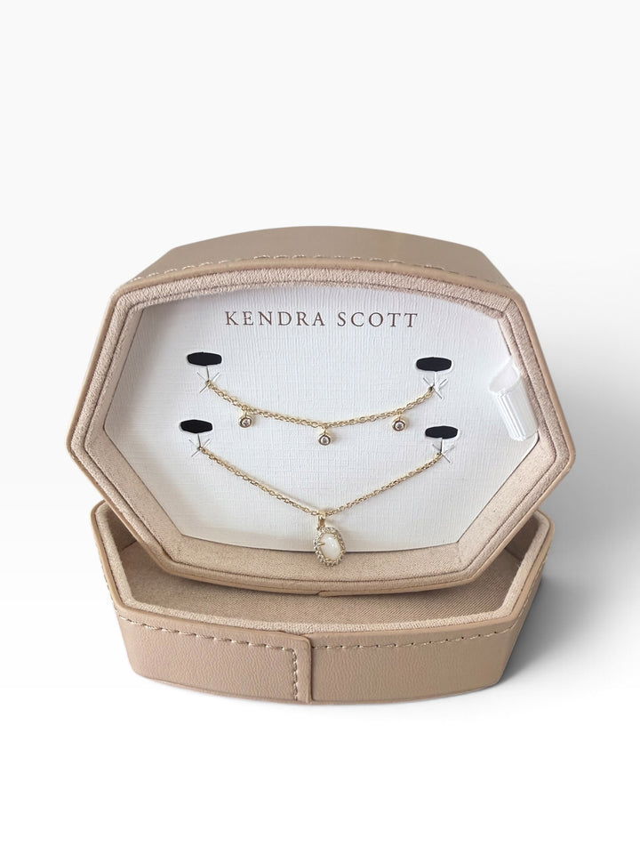Two delicate gold necklaces, one with three small crystals and one with a stone pendant, in a Kendra Scott Daphne Amelia Jewelry Box Set.