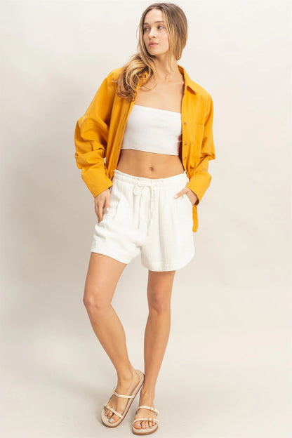 Beige drawstring pleated shorts, available in sizes XS–XL. Features adjustable waist and side pockets.