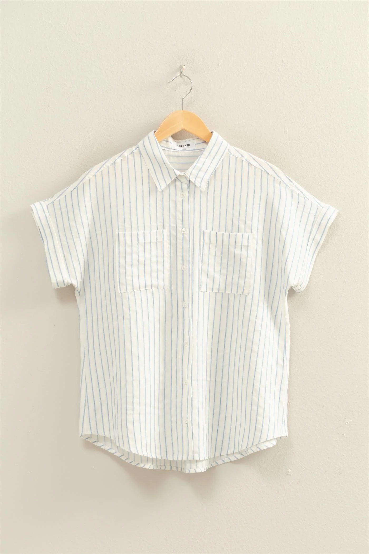 White shirt with blue vertical stripes, button-up, dolman sleeves, two chest pockets, relaxed fit. Available in S–XL.