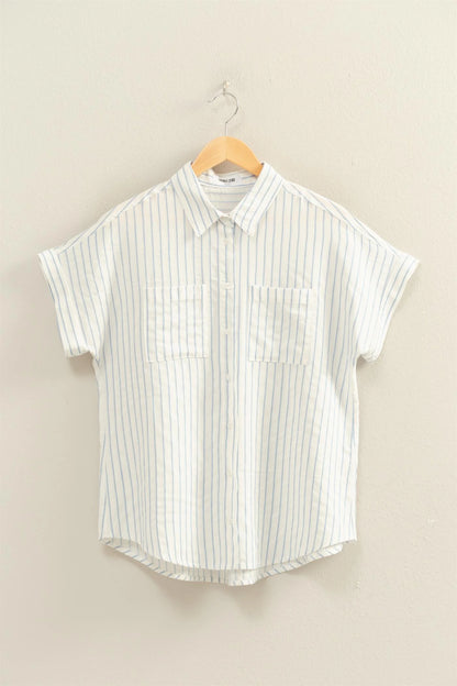 White shirt with blue vertical stripes, button-up, dolman sleeves, two chest pockets, relaxed fit. Available in S–XL.
