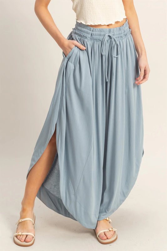 Light blue Tulip Hem Wide-Leg Pants with side slits, elastic drawstring waist, and pockets. Available in sizes XS–XL.