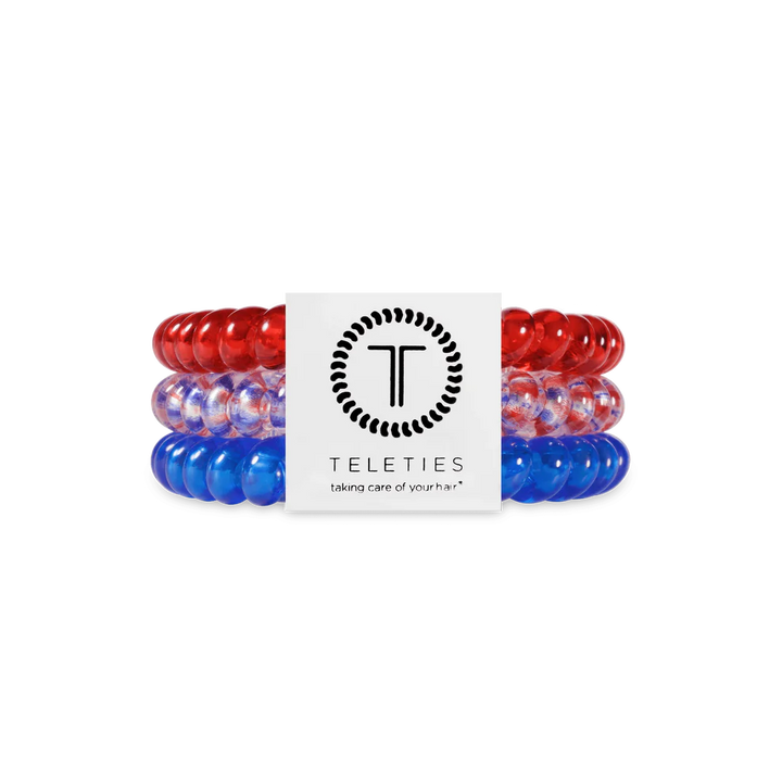 Three TELETIES Hair Ties—red, clear with blue, and blue—in branded white packaging. Available in small and large sizes.