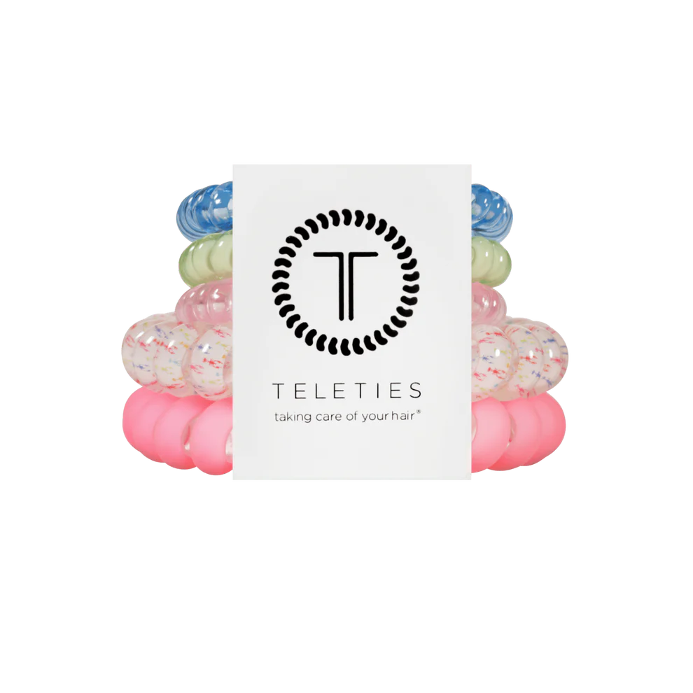 Four TELETIES Hair Ties—blue, green, white speckled, pink—shown with branded card. Available in multiple sizes.