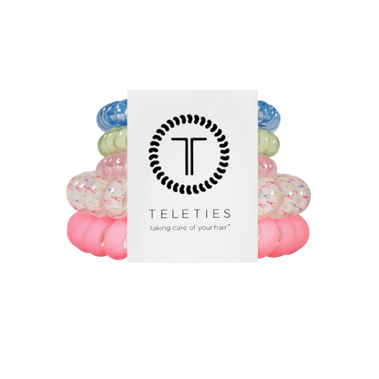 Four TELETIES Hair Ties—blue, green, white speckled, pink—shown with branded card. Available in multiple sizes.