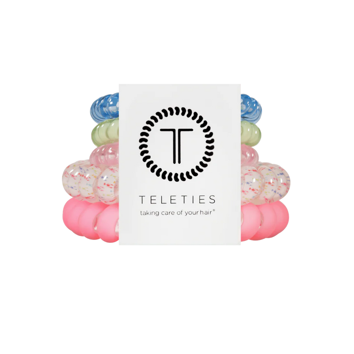 Four TELETIES Hair Ties—blue, green, white speckled, pink—shown with branded card. Available in multiple sizes.