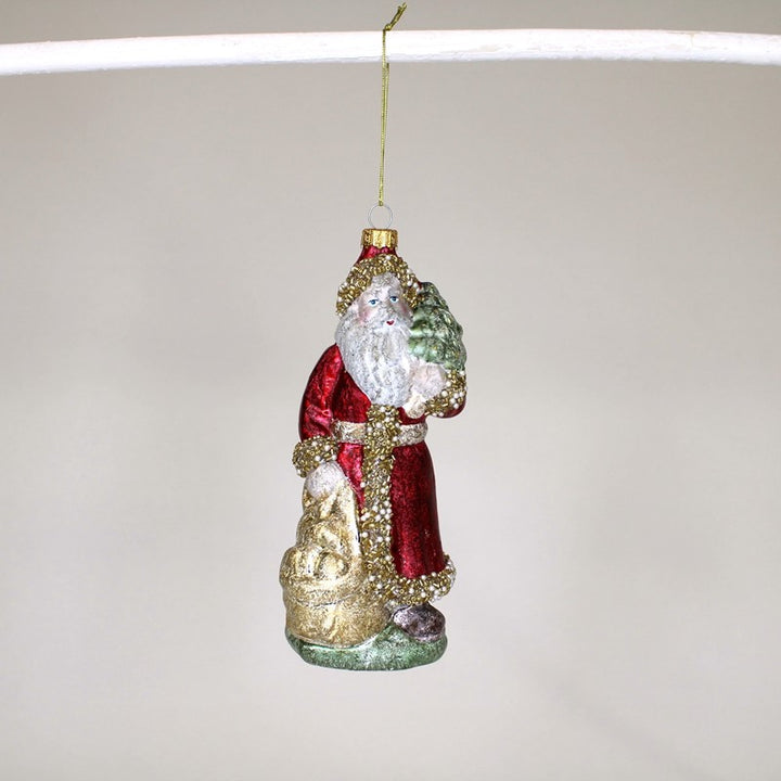 7″ Beaded Santa blown glass ornament in red coat with gold trim, holding tree and sack.