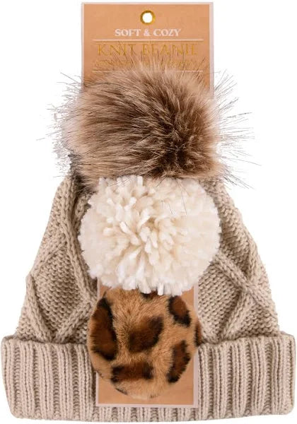 Beige knit beanie with folded brim; includes 3 interchangeable pom poms. Sizes available: S/M, L/XL.