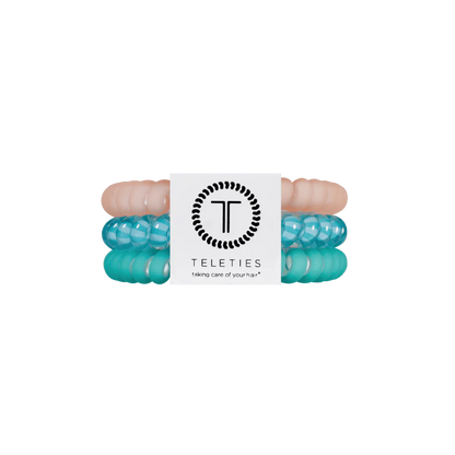 Three TELETIES Hair Ties in pastel pink, translucent turquoise, and opaque turquoise with white label. Available in small and large.
