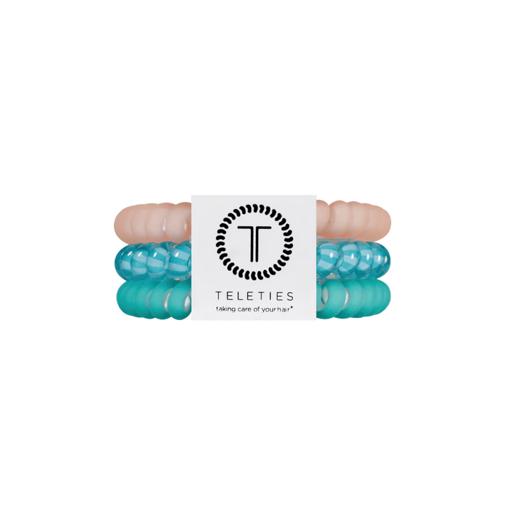 Three TELETIES Hair Ties in pastel pink, translucent turquoise, and opaque turquoise with white label. Available in small and large.