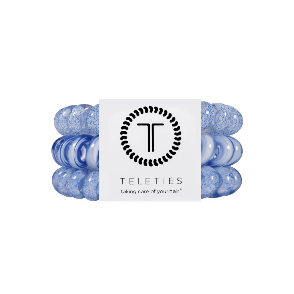 Pack of two blue TELETIES Hair Ties with "TELETIES" label and "taking care of your hair" tagline; available in multiple sizes.