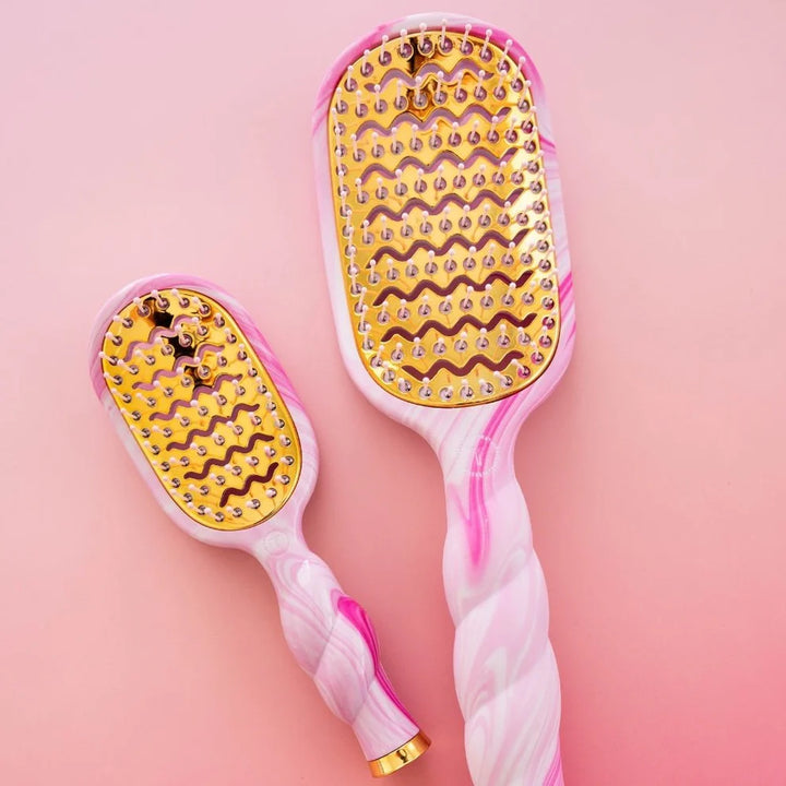 Two Pinch Me! Tie Dye Pink Vented Hair Brushes with gold bristles and paddle bases; available in large quick-heating and small sizes.